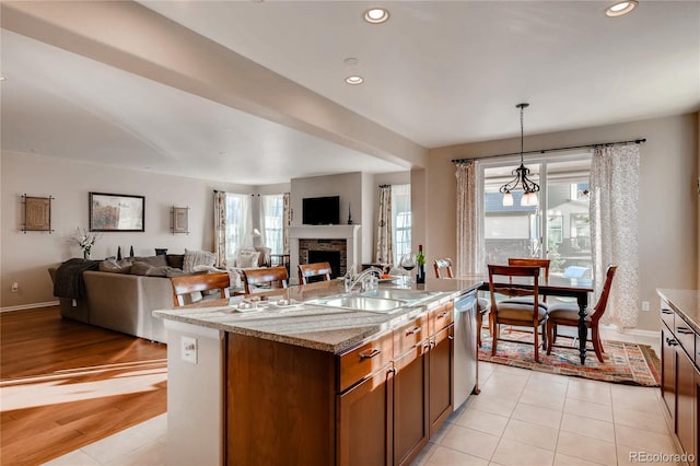 kitchen featuring stainless steel dishwasher, open floor plan, a stone fireplace, and a sink