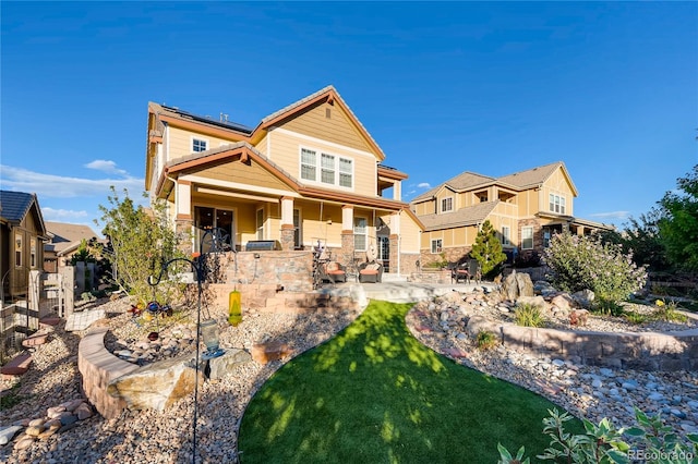 craftsman-style house with a patio area, stone siding, and solar panels