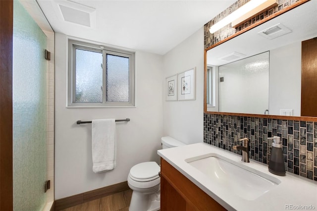 bathroom featuring backsplash, toilet, a shower with door, wood finished floors, and baseboards