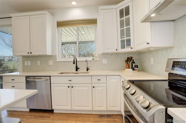 kitchen with a sink, white cabinets, stainless steel appliances, and under cabinet range hood