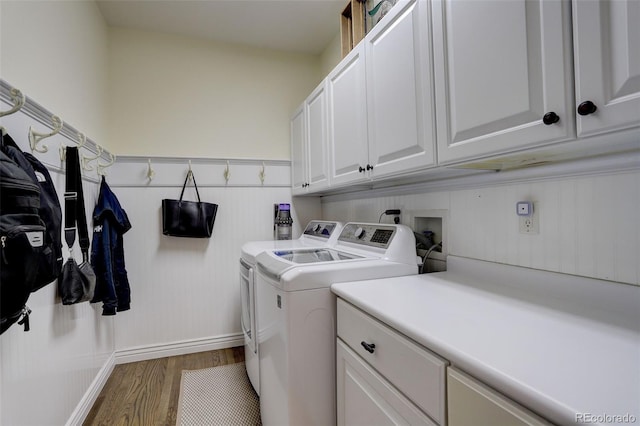 laundry area with wood finished floors, baseboards, cabinet space, and washing machine and clothes dryer