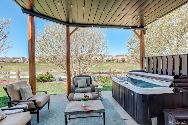 view of patio / terrace featuring fence, an outdoor living space, and a hot tub