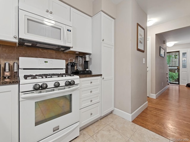 kitchen featuring white appliances, baseboards, white cabinets, backsplash, and light tile patterned flooring