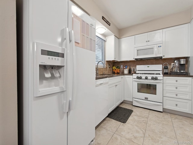 kitchen featuring dark countertops, white appliances, white cabinetry, and a sink