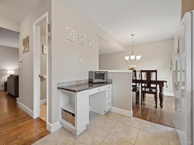 kitchen featuring baseboards, white cabinets, freestanding refrigerator, open shelves, and decorative light fixtures