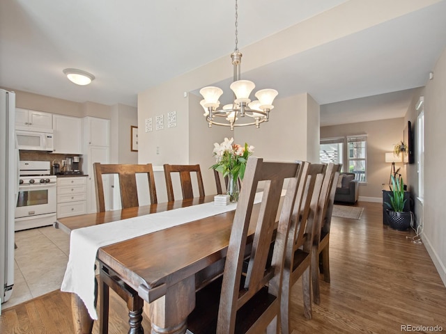 dining room with a notable chandelier, light wood finished floors, and baseboards