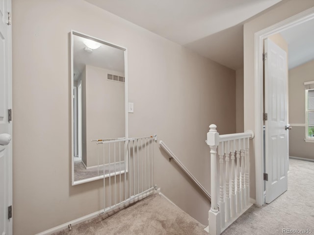 hall featuring visible vents, carpet flooring, and an upstairs landing