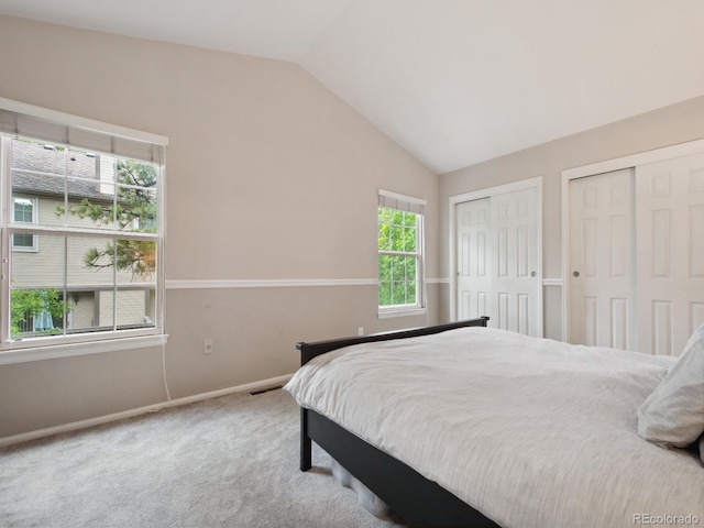 carpeted bedroom with lofted ceiling, visible vents, baseboards, and multiple closets