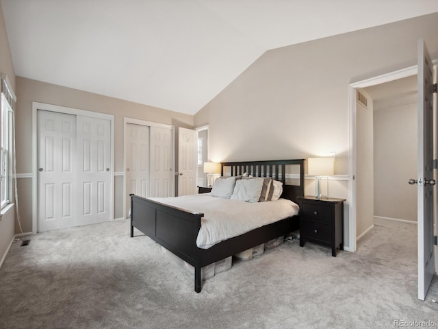 carpeted bedroom with vaulted ceiling, visible vents, and multiple closets