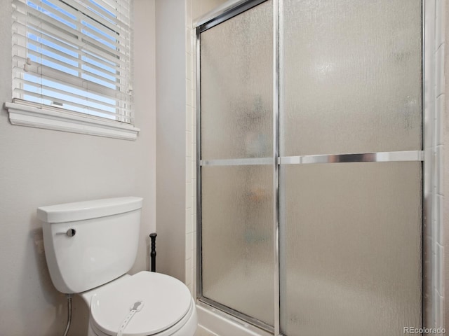 full bathroom featuring toilet and a shower with shower door