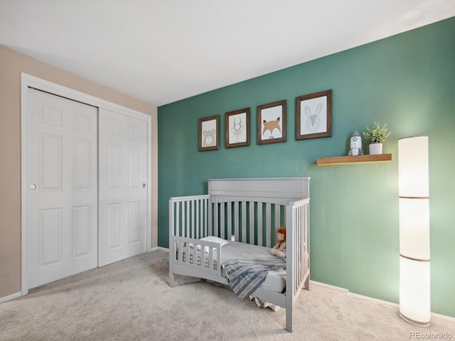 bedroom featuring carpet, a closet, a crib, and baseboards