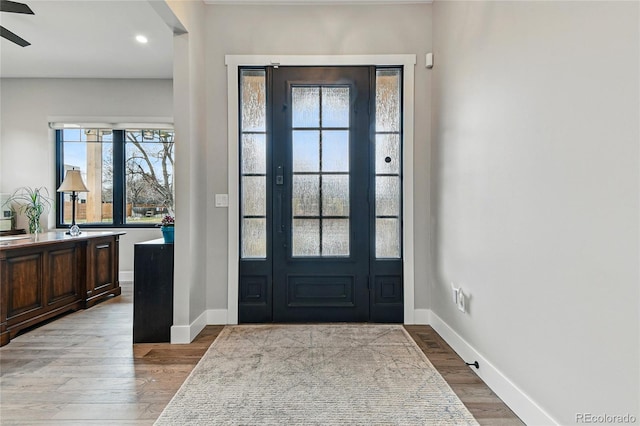 foyer featuring a ceiling fan, light wood-type flooring, and baseboards