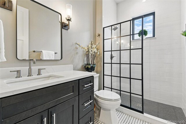 full bath with a tile shower, toilet, and vanity