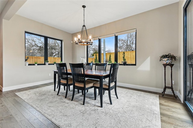 dining room featuring plenty of natural light, baseboards, an inviting chandelier, and wood finished floors