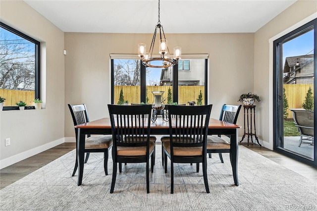 dining space featuring an inviting chandelier, wood finished floors, and baseboards