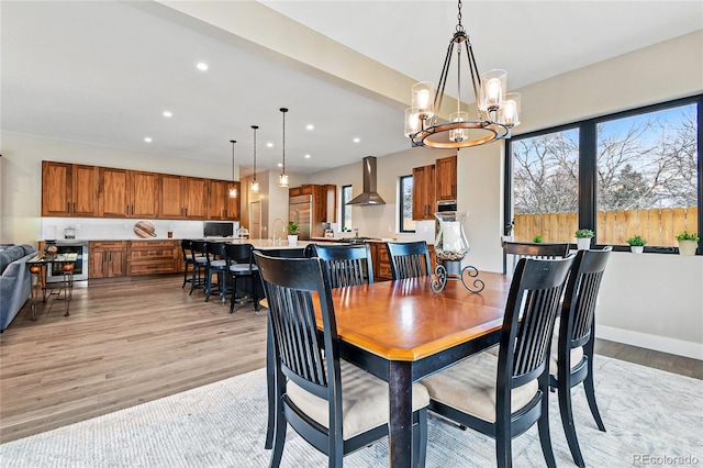 dining room featuring recessed lighting, light wood-type flooring, baseboards, and a notable chandelier