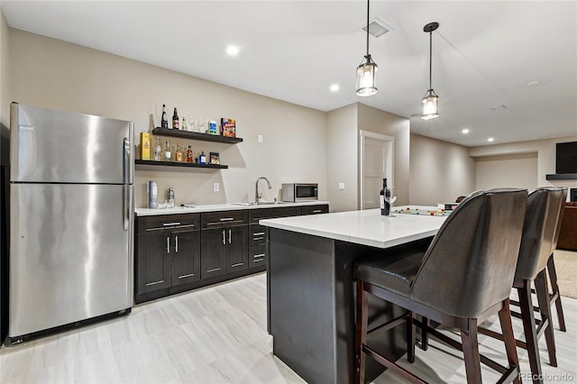 kitchen with visible vents, a sink, light countertops, appliances with stainless steel finishes, and a kitchen breakfast bar