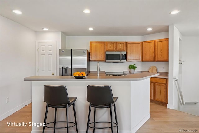 17145 Waterhouse Cir Unit F, Parker, CO 80134 - kitchen with appliances with stainless steel finishes, light wood finished floors, brown cabinets, recessed lighting, and a kitchen bar