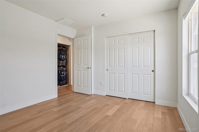 17145 Waterhouse Cir Unit F, Parker, CO 80134 - unfurnished bedroom featuring stacked washer / dryer, light wood-style floors, and a closet