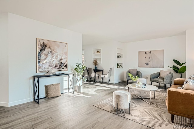 living area with built in shelves, wood finished floors, and baseboards