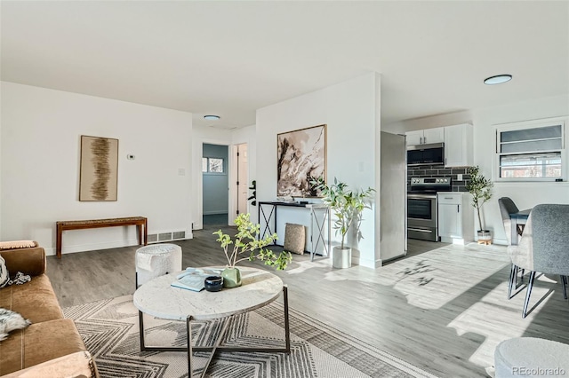 living area with wood finished floors, visible vents, and baseboards