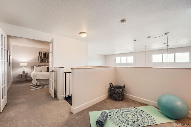 workout room with a textured ceiling, carpet flooring, and baseboards