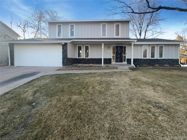 traditional-style house featuring a front yard, covered porch, concrete driveway, a garage, and stone siding