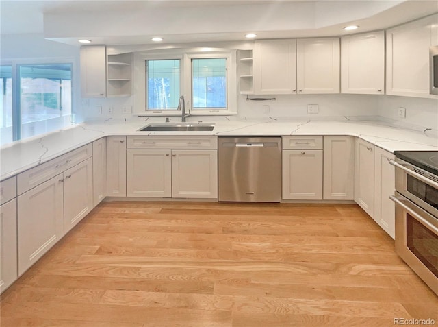 kitchen featuring open shelves, light wood-style floors, appliances with stainless steel finishes, and a sink