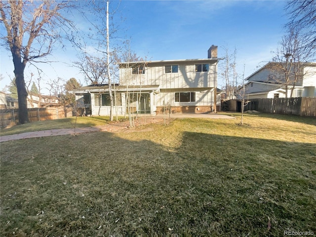 back of property with a patio, a lawn, a fenced backyard, and a chimney