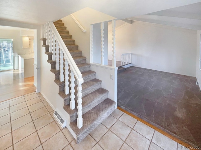 stairway with tile patterned floors, visible vents, and lofted ceiling with beams