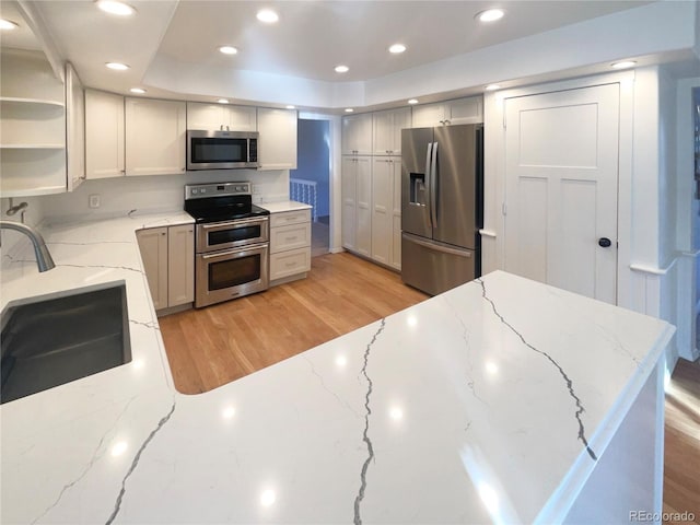 kitchen with a sink, recessed lighting, light wood-style flooring, appliances with stainless steel finishes, and open shelves