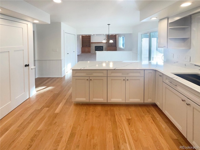 kitchen with open shelves, light wood-type flooring, a peninsula, and wainscoting