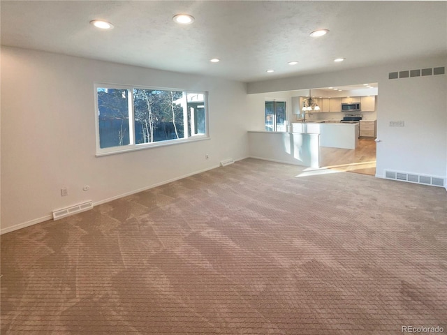 unfurnished living room with recessed lighting, visible vents, and carpet flooring