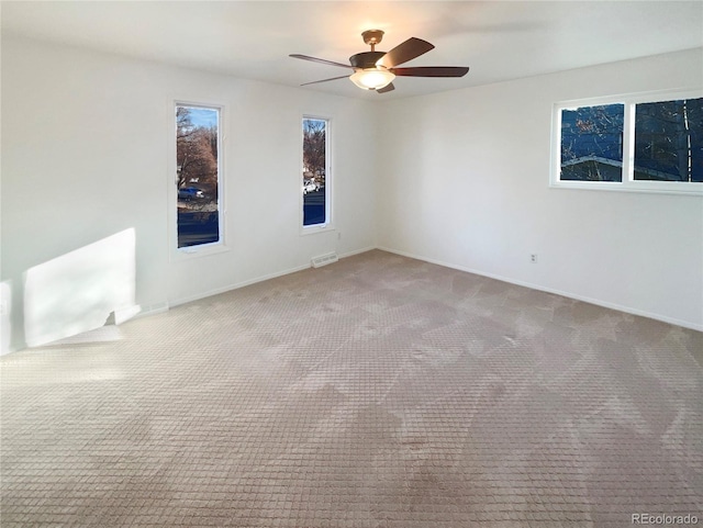 carpeted spare room with a ceiling fan, visible vents, and baseboards