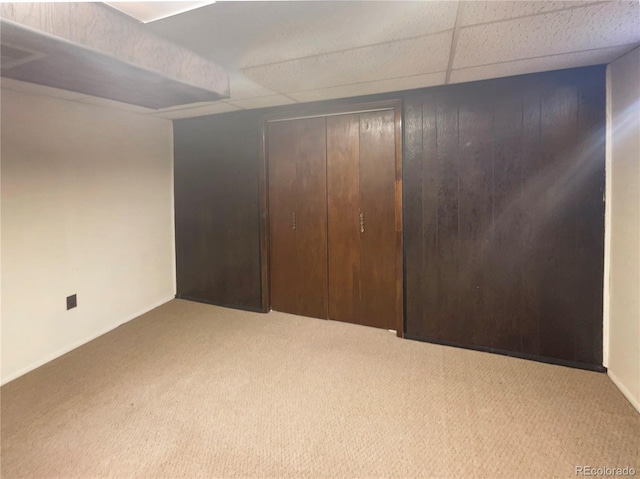 unfurnished bedroom featuring carpet flooring, a paneled ceiling, and a closet