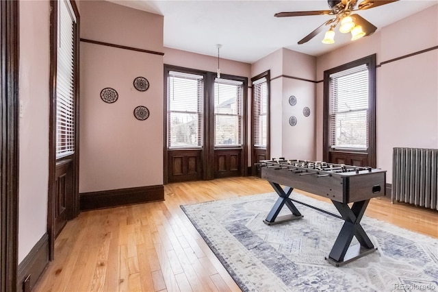 interior space with baseboards, radiator heating unit, a ceiling fan, and light wood-style floors