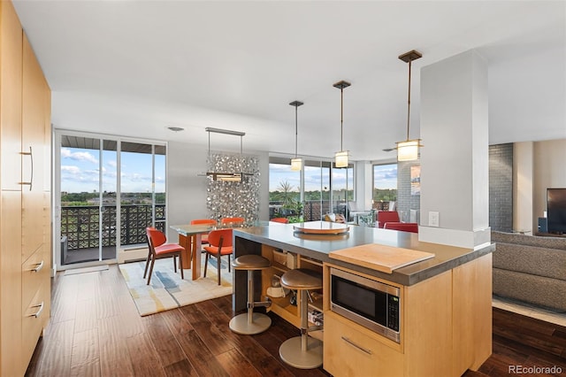 4570 E Yale Ave Unit 1104, Denver, CO 80222 - kitchen featuring stainless steel microwave, light brown cabinets, dark wood finished floors, open floor plan, and pendant lighting