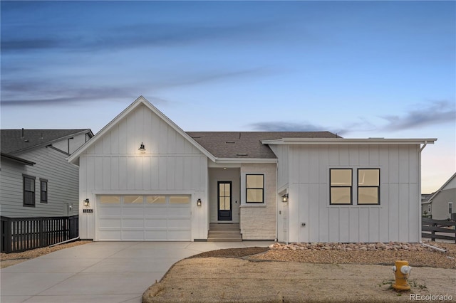 view of front of house featuring fence, roof with shingles, board and batten siding, concrete driveway, and an attached garage