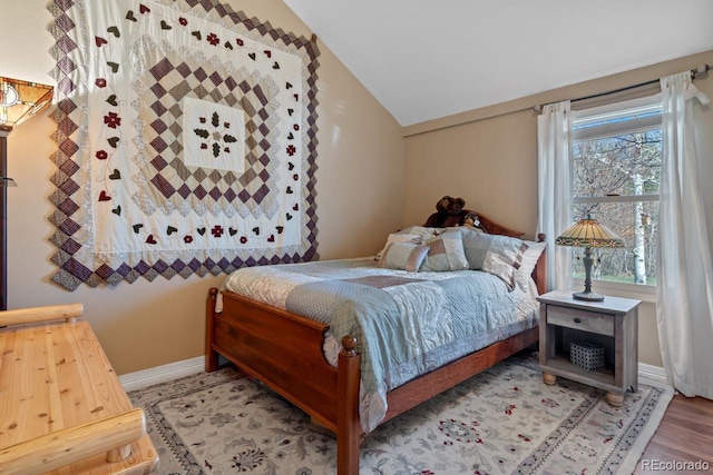 bedroom featuring wood finished floors, baseboards, multiple windows, and lofted ceiling
