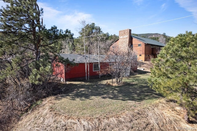 view of side of property with a yard, crawl space, and a chimney