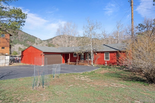 ranch-style home with a mountain view, a front lawn, a garage, and aphalt driveway