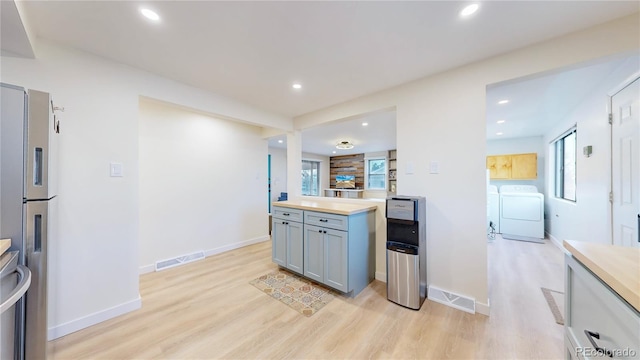 kitchen with visible vents, washing machine and dryer, light wood-type flooring, gray cabinets, and stainless steel refrigerator