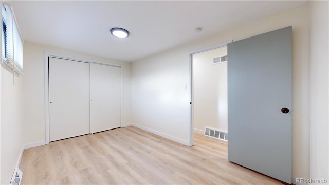 unfurnished bedroom with visible vents, baseboards, light wood-style floors, and a closet