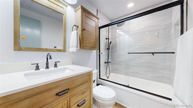 bathroom featuring combined bath / shower with glass door, recessed lighting, toilet, and vanity