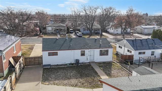 back of property featuring a residential view, cooling unit, roof with shingles, and fence