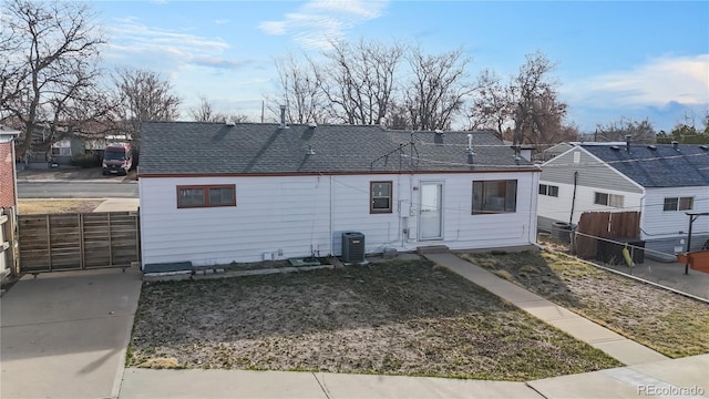 back of house with a residential view, fence, central AC, and roof with shingles