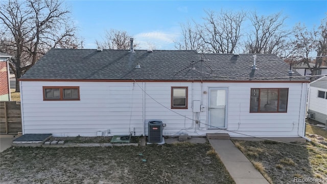 back of house featuring cooling unit, a lawn, a shingled roof, and fence