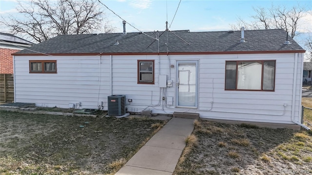 back of house featuring a yard, roof with shingles, and central AC unit