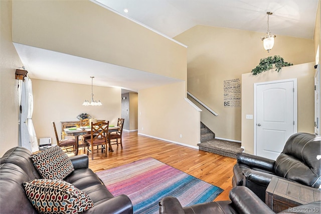 living area featuring high vaulted ceiling, baseboards, stairway, and light wood finished floors