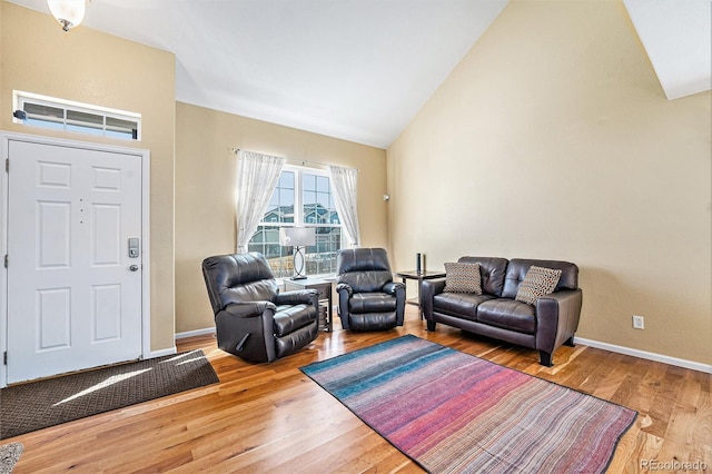 living area with high vaulted ceiling, baseboards, and wood finished floors